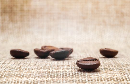 several coffee beans on a matting macro beige background closeup