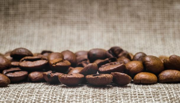 many coffee beans on a matting macro beige background close up