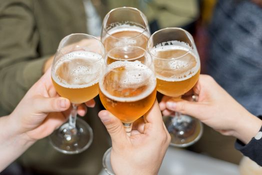 Group of friends drinking beer, toasting, at pub