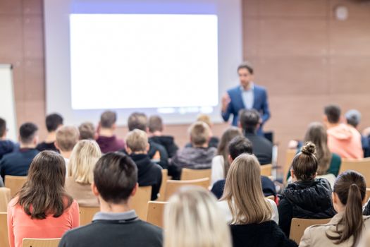 Speaker giving a talk in conference hall at business event. Audience at the conference hall. Business and Entrepreneurship concept. Focus on unrecognizable people in audience.