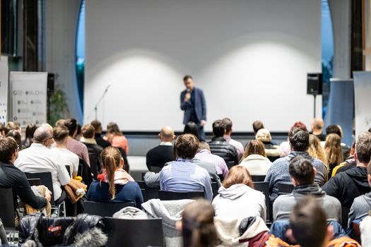 Speaker giving a talk in conference hall at business event. Audience at the conference hall. Business and Entrepreneurship concept. Focus on unrecognizable people in audience.
