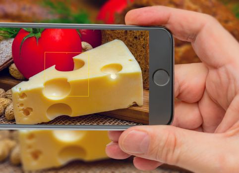 Cheese on smartphone screen. Vegetarian still life. Cheese and tomatoes.