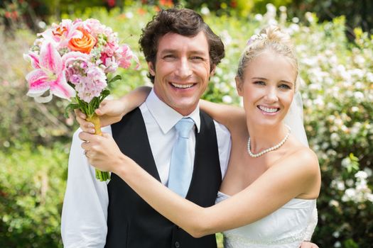 Romantic newlywed couple smiling at camera on their wedding day in the countryside