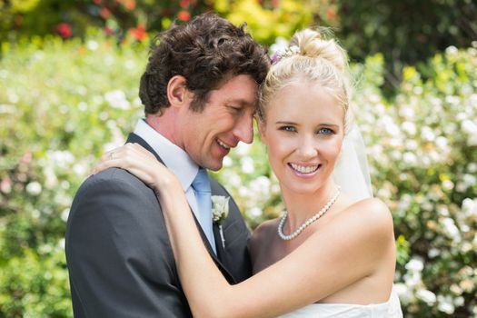 Romantic smiling newlyweds hugging each other in the countryside