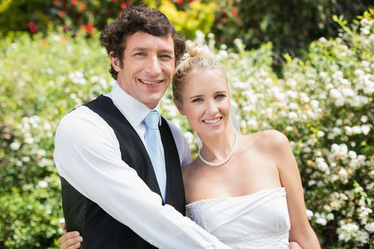 Romantic happy newlywed couple smiling at camera in the countryside