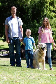 Portrait of a happy family standing in the park with their dog