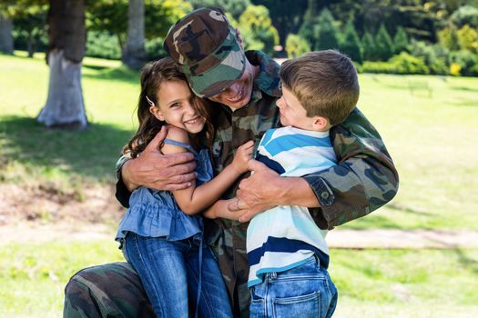 Happy soldier reunited with his son and daughter in the park on a sunny day