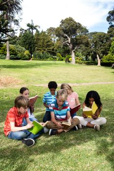 Children reading book in the park on a sunny day