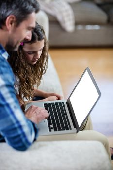 Father and daughter using laptop at home