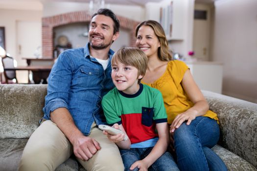 Parents and son watching television in living room at home
