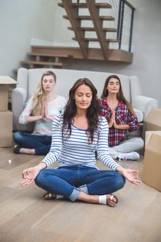 Three friends performing yoga together in their new house