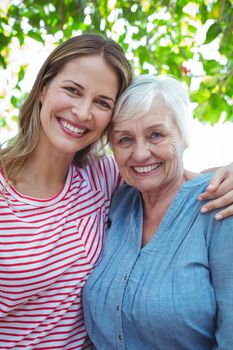 Portrait of happy mother and daughter with arm around while standing outdoors