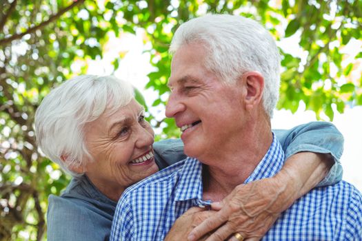 Close-up of cheerful senior couple hugging while standing outdoors
