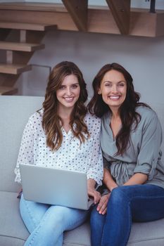 Two beautiful women using a laptop in living room at home