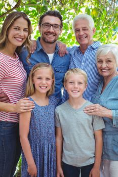 Portrait of smiling multi generation family standing against tree