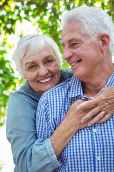 Cheerful retired couple hugging while standing outdoors