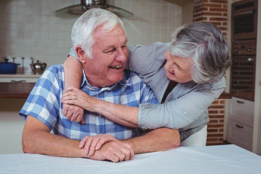 Romantic senior couple embracing in kitchen at home