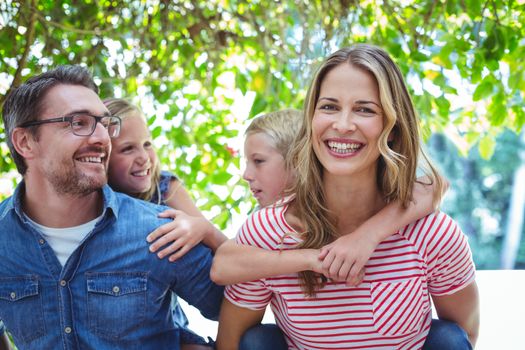 Cheerful parents giving piggy back to children while standing outdoors