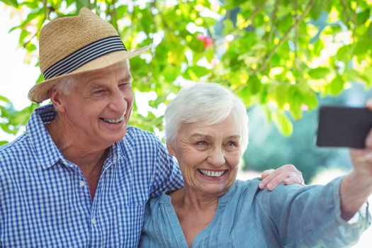 Happy retired couple taking selfie while standing outdoors