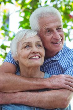Cheerful senior couple hugging while standing outdoors