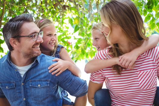 Smiling parents giving piggy back to children while standing outdoors