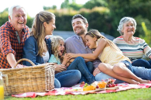 Multi-generation family laughing while sitting on blanket