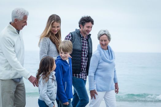 Happy family walking at beach against sky