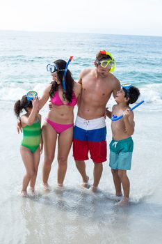 Family wearing diving goggles while standing on sea shore at beach