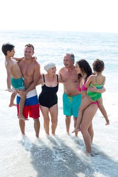 High angle view of happy family standing on sea shore at beach 