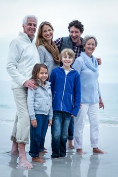 Portrait of happy family standing at beach against sky
