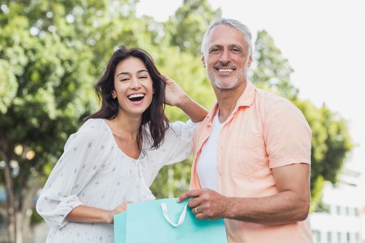 Portrait of happy couple with shopping bags standing outdoors