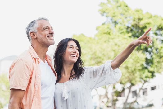 Happy woman pointing to man while standing outdoors