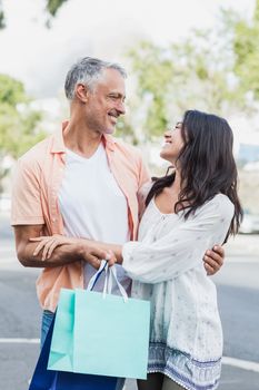 Happy couple with shopping bags standing outdoors