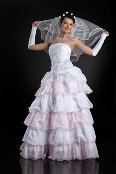 Young beautiful woman in a wedding dress on a studio background