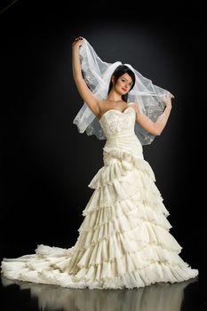 Young beautiful woman in a wedding dress on a studio background