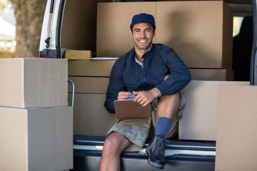Portrait of smiling delivery person with clipboard while sitting in van