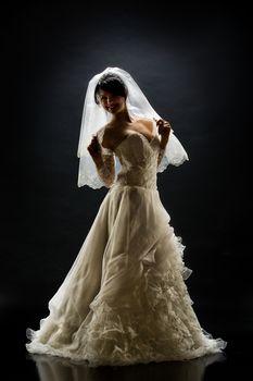 Young beautiful woman in a wedding dress on a studio background