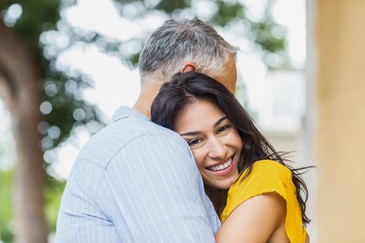 Portrait of cheerful woman hugging man outdoors