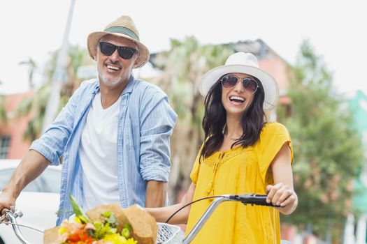 Portrait of happy couple with cycles standing outdoors