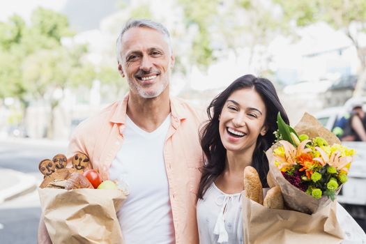 Portrait of happy couple with grocery bags standing outdoors