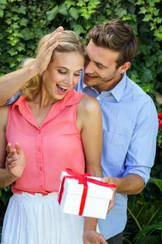 Romantic happy man giving gift to woman at front yard