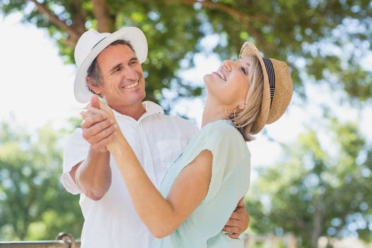 Cheerful couple dancing outdoors against trees