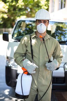 Portrait of worker with pesticide sprayer while standing by van
