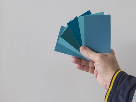 hand of a man with different color swatches for determining the right color of paint on a wall