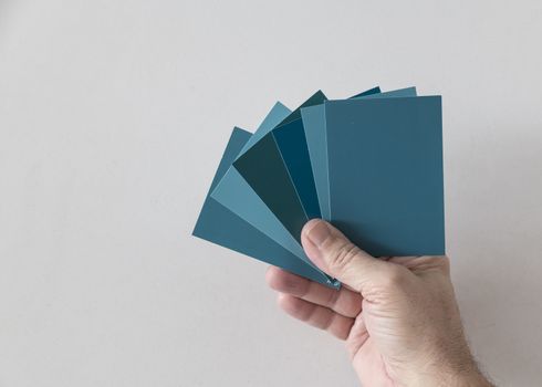 hand of a man with different color swatches for determining the right color of paint on a wall