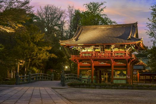 Bridge named bridge of the gods "神橋"　(shinbashi) and central gate named the cherry door "桜門" (sakuramon) of the Shintoist Nezu shrine of the 18th century in Tokyo at sunset.