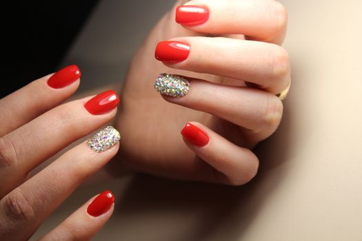 Manicure design nails is bright red and rhinestones