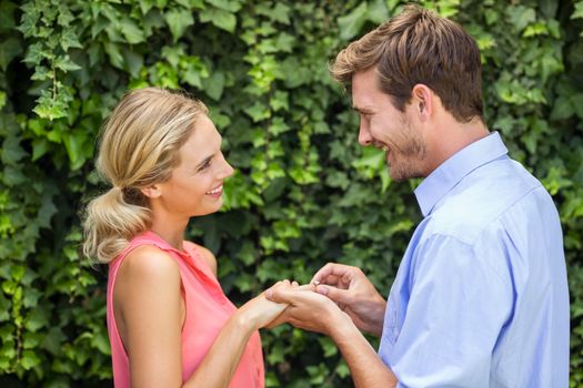 Romantic man wearing ring to woman at front yard