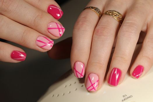 Stylish trendy female manicure. Beautiful young woman's hands on pink