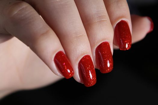 Close up on beautiful female hands with sexy red manicure. Red velvet background.